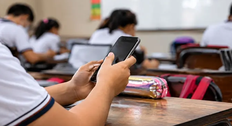Estudiantes en escuela con celulares guardados